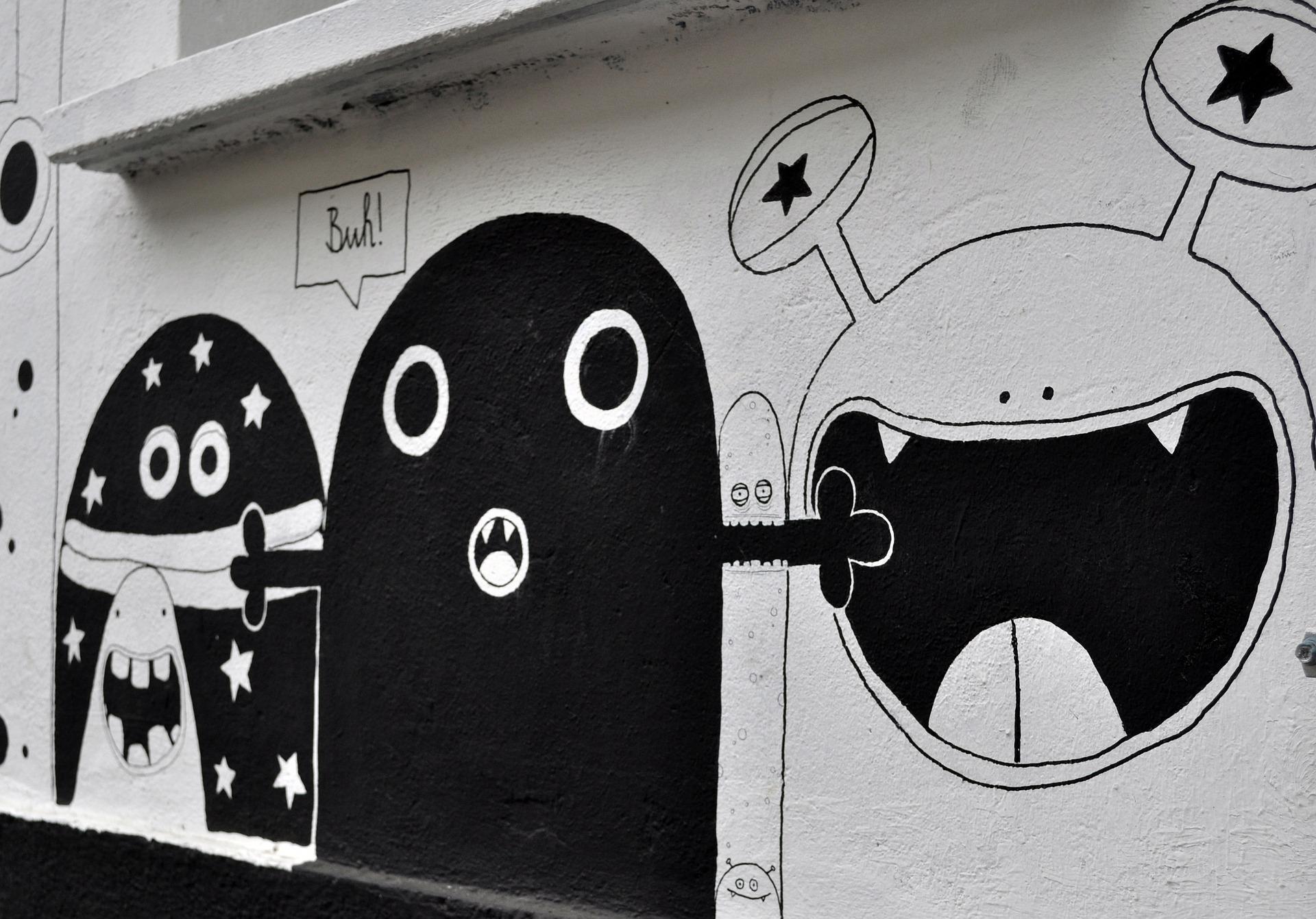 Graffity auf grauer Hauswand, süß gezeichnete Monster, eins davon sagt 